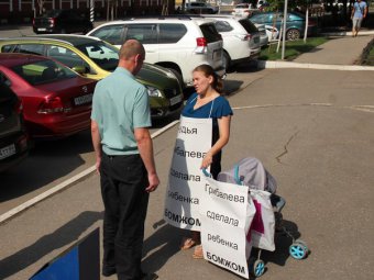 Беременная женщина с маленьким ребенком проводит акцию протеста у входа в облсуд