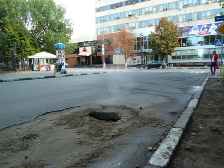 Напротив входа в Липки из засыпанного песком провала в дороге идет пар