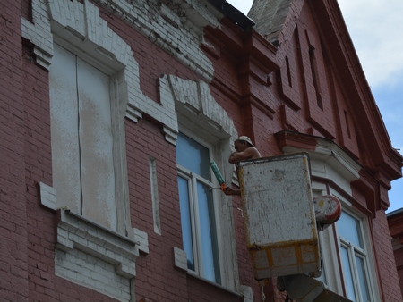 Ремонт фасадов на Московской. Рабочие красят дом с заколоченными окнами и без крыши