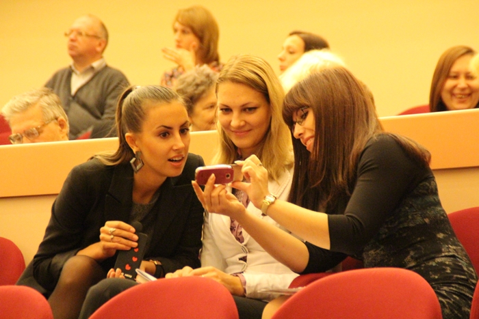 Девушки смотрят фотографии во время заседания Саратовской городской думы